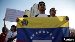 An opposition supporter holds a Venezuelan flag during a protest against Venezuelan President Nicolas Maduro's government, in Caracas, March 30, 2017.