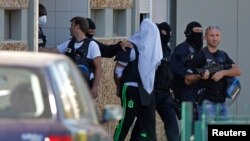 The suspect held over an attack against a gas company site is escorted by police officers during investigations in Saint-Priest, near Lyon, France, June 28, 2015. 