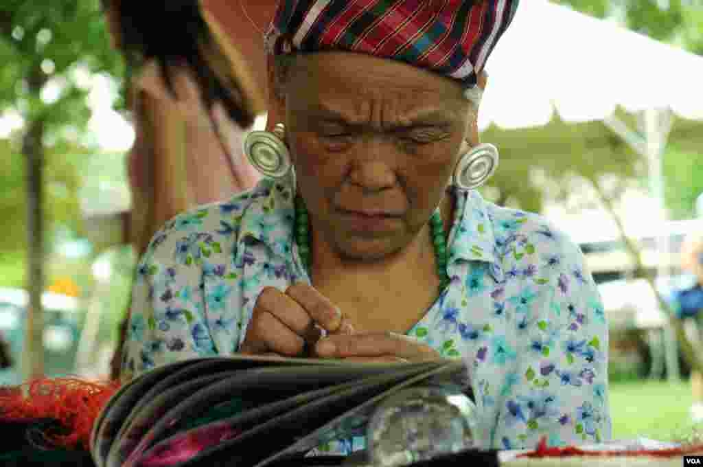 An artisan untangles thread and readies a needle in the Chinese textiles tent at the Smithsonian Folklife Festival in Washington, June 25, 2014. (Regina Catipon/VOA)