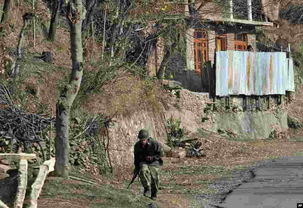 An Indian army soldier runs for cover near the site of a gunbattle with suspected rebels in Gingal, some 90 kilometers (56 miles) north of Srinagar, India, Friday, Dec. 5, 2014.