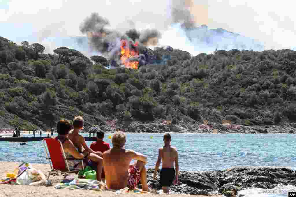 People look at a forest fire in La Croix-Valmer, near Saint-Tropez, France. Firefighters battle blazes that have consumed swathes of land in southeastern France for a second day, with one inferno out of control near the chic resort of Saint-Tropez, emergency services say.