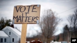A handmade sign stuck in a snowbank on a rural road urges citizens to vote, Tuesday, Nov. 4, 2014, in Searsmont, Maine.