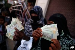 FILE - Yemeni women display paper currency in Sanaa, Yemen, Nov. 14, 2015.