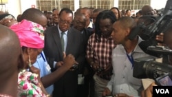 Zimbabwe Minister of Agriculture Joseph Made (in suit), who says the yield and quality of tobacco in 2017 are due to good rains, is shown how the new tobacco electronic auctioning system works, in Harare, March 15, 2017. (S. Mhofu/VOA)