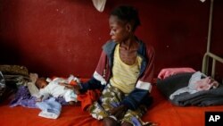 A severely malnourished child lays by his mother at Bangui's pediatric center in Bangui, Dec. 17, 2013.