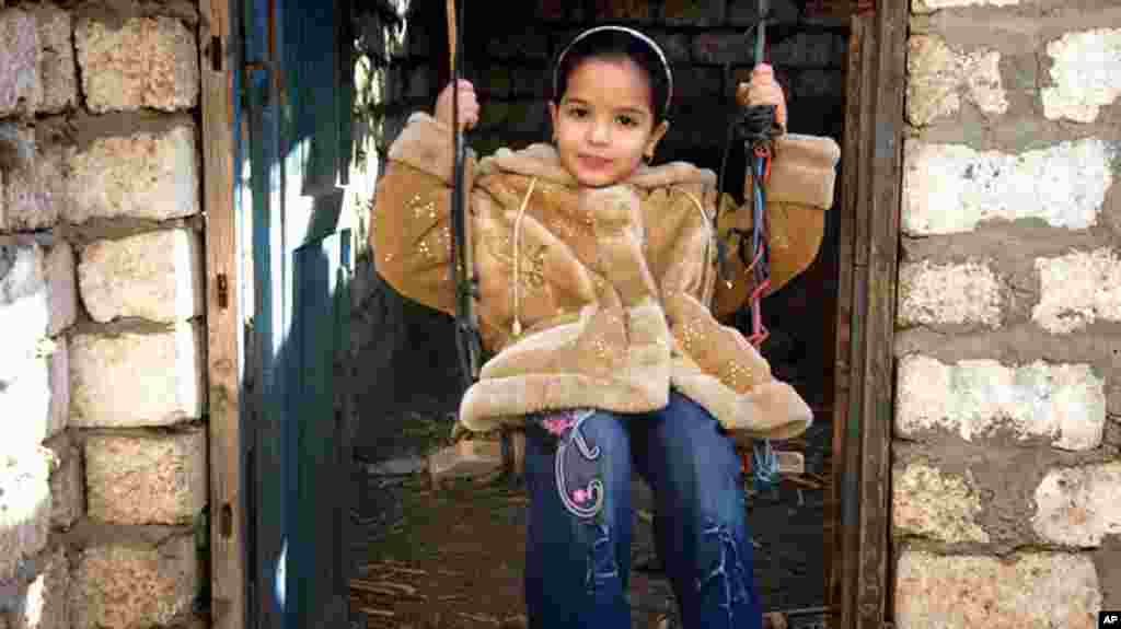 A young girl swings in the doorway to her the family's baking shed, Kafr Torky, February 13, 2011 (VOA photo- E. Arrott)