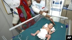 An Indian mother, left, looks at her baby girl, born prematurely, at Rajasthan Hospital's neo-natal intensive care unit in Ahmadabad, India, Feb. 28, 2008.