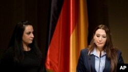 NSU kurbanlarının yakınları Semiya Şimşek (sağda) ve Gamse Kubasik, Berlin'de Şubat 2012'de düzenlenen anma töreninde konuşurken