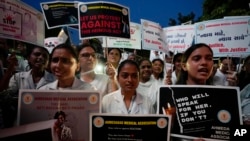 Doctors and medical students hold placards and candles during a protest against the rape and killing of a trainee doctor at a government hospital in Kolkata last week, in Ahmedabad, India, Aug. 17, 2024.