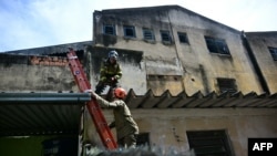 Firefighters leave after extinguishing a fire in a textile factory that specializes in making Carnival costumes and police uniforms in the northern part of Rio de Janeiro, Brazil, on Feb. 12, 2025.