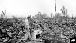 FILE - In this Sept. 7, 1945, photo, an unidentified man stands next to a tiled fireplace where a house once stood in Hiroshima, Japan. The Los Alamos Historical Museum recently announced it won't be hosting a Japanese traveling exhibit until the parties can work out their differences over the theme.