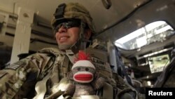 El soldado de EE.UU Moisés Ochoa del 2do Batallón de Infantería, lleva en su chaleco camuflado, a prueba de balas, un juguete de peluche para su hijo de nueve meses. El militar viaja a bordo de un vehículo blindado en la provincia de Kandahar, Afganistán.Foto: Reuters