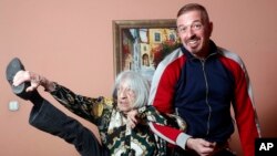 Agnes Keleti, mantan atlet senam Hongaria, peraih medali emas Olimpiade, menunjukkan fleksibilitasnya saat berfoto bersama putranya Rafael di apartemennya di Budapest, Hongaria, Rabu, 8 Januari 2020.