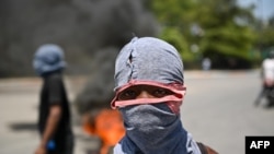 FILE - A young demonstrator wears a mask during a protest against insecurity, on August 7, 2023, near the Prime Minister's official house in Port-au-Prince, Haiti.