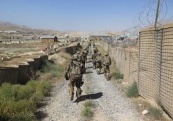 FILE - U.S. military advisers from the 1st Security Force Assistance Brigade walk at an Afghan National Army base in Maidan Wardak province, Afghanistan, August 6, 2018.