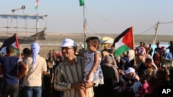 In this Sept. 25, 2019 photo, Palestinian activist Ahmed Abu Artima holds his daughter during an alternative protest he organized near the separation fence between the Gaza Strip and Israel.