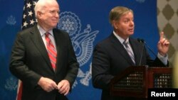U.S. Senator Lindsey Graham (R) speaks as Senator John McCain looks on during a news conference in Cairo, August 6, 2013. 
