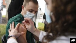 Colleen Teevan, System Pharmacy Clinical Manager at Hartford HealthCare, administers the Pfizer-BioNTech vaccine for COVID-19 to healthcare worker Connor Paleski outside of Hartford Hospital, Monday, Dec. 14, 2020, in Hartford, Conn. (AP Photo/Jessica Hil