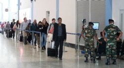FILE - Sri Lankan health officials and military personnel monitor passengers through a thermal scanner at the Katunayake International airport in Colombo, Sri Lanka, Jan. 30, 2020.