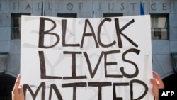 A supporter of Black Lives Matter holds a sign during a protest outside the Hall of Justice as they demonstrate against the death of George Floyd, in Los Angeles, California, on June 10, 2020. 