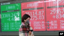 A woman walks by an electronic stock board of a securities firm in Tokyo, Nov. 10, 2020. 