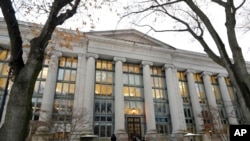 In this Thursday, Dec. 5, 2019 photo passers-by walk near an entrance to a building at Harvard Law School, in Cambridge, Mass.