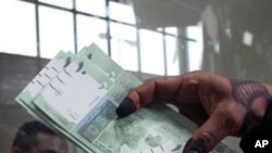 A woman displays Sudan's new currency at the central bank in Khartoum, Sudan. The Sudanese government began circulating a new edition of the Sudanese pound on Sunday as a precautionary measure following the loss of oil revenues resulting from South Sudan'