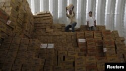 Two workers unload boxes of aid inside a warehouse at the Mrajeeb Al Fhood refugee camp for Syrian refugees, 20 kilometers east of the city of Zarqa, Jordan, April 29, 2013.