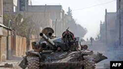 Turkey-backed Syrian fighters ride a tank in the town of Saraqib in the eastern part of the Idlib province in northwestern Syria. Syrian rebels re-entered the northwestern crossroads town of Saraqib lost to government forces earlier this month. But fighting continued in the outer part of the town today, an AFP reporter says. <br />
