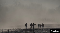 Un grupo de migrantes es detenido por miembros de la Guardia Nacional de Estados Unidos en Eagle Pass, Texas, visto desde Piedras Negras, México.