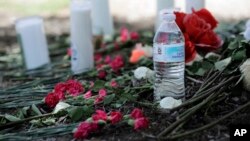  A bottle of water, flowers, candles, and stuffed animals help form a makeshift memorial in the parking lot of a Walmart store near the site where authorities discovered a tractor-trailer packed with immigrants in San Antonio, July 24, 2017. 