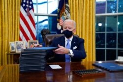 FILE - President Joe Biden signs his first executive orders, including halting work on a border wall, in the Oval Office of the White House in Washington, Jan. 20, 2021.