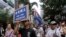 FILE - Protesters hold placards and wave colonial-era flags at an annual pro-democracy rally in Hong Kong, July 1, 2016. As the territory prepares for legislative elections, a new pledge of loyalty to China candidates are required to sign is creating friction.
