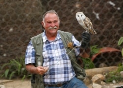 Gary Strafford, a Zimbabwean falconer, holds an owl inside one of the cages at his bird sanctuary, Kuimba Shiri, near Harare, Zimbabwe, June 17, 2020.