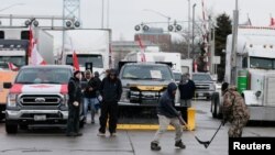 تجمع رانندگان کامیون در کانادا. دو معترض در حال بازی هاکی در جاده‌ای که توسط کامیون‌داران مسدود شده است - ۲۰ بهمن ۱۴۰۰