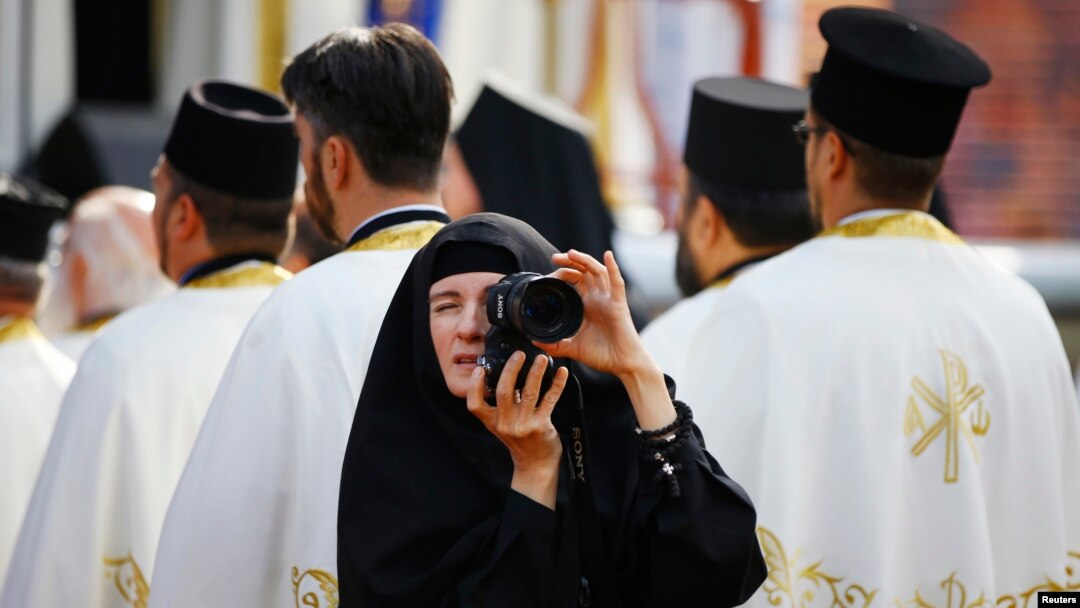 Seorang biarawati mengambil gambar di tengah umat yang merayakan 1.700 tahun Fatwa Milan, atau fatwa toleransi umat Kristen, di kota Nis, Serbia (6/10). (Reuters/Marko Djurica)