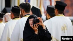 Seorang biarawati mengambil gambar di tengah umat yang merayakan 1.700 tahun Fatwa Milan, atau fatwa toleransi umat Kristen, di kota Nis, Serbia (6/10). (Reuters/Marko Djurica)