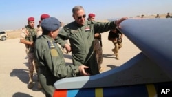 In this Oct. 10, 2015, Iraqi Defense Minister Khaled al-Obeidi, center, inspects a first Chinese drone to be used by the Iraqi Air Force before sending it to bomb Islamic State group positions at an airbase in Kut.