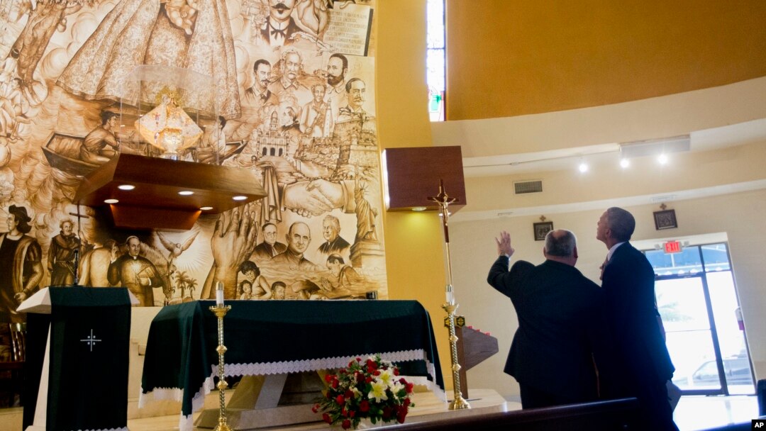 President Barack Obama learns about the Shrine of Our Lady of Charity from Father Juan Rumin Dominguez during an unannounced stop at the Miami church, May 28, 2015.