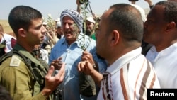 Palestinian farmers argue with an Israeli soldier as they try to plant olive trees during a protest against what they say is land confiscation for Jewish settlements in the Jordan Valley, a hotly contested part of the occupied West Bank, April 8, 2014. 