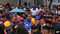 El presidente venezolano, Nicolás Maduro, saluda a jóvenes partidarios que marchan contra las sanciones impuestas por Estados Unidos a Venezuela, en Caracas, el viernes 17 de mayo de 2024.