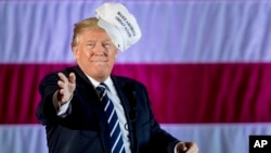 FILE - President-elect Donald Trump throws a hat into the audience while speaking at a rally in a DOW Chemical Hanger at Baton Rouge Metropolitan Airport, Dec. 9, 2016