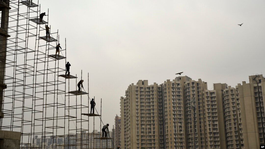 Para pekerja India berdiri di atas batang baja yang ditancapkan di atas tanah ke atas gedung yang sedang dibangun di Greater Noida, India, 12 Februari 2018. (Foto: dok).
