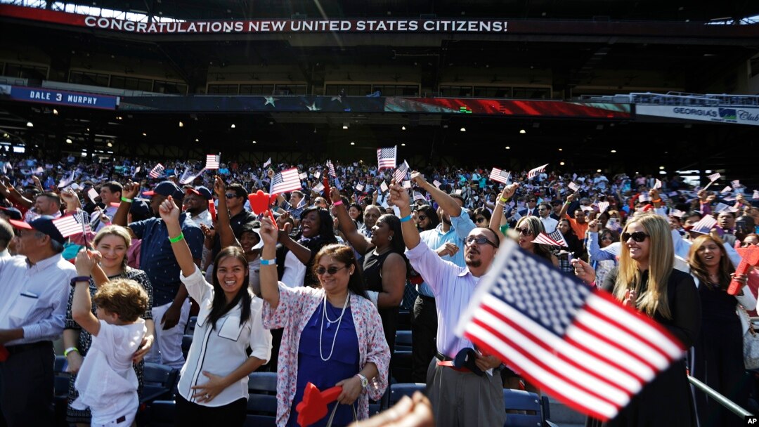 Orang-orang bersorak setelah mengucapkan janji setia dalam upacara naturalisasi bagi 755 warga negara AS yang baru di Turner Field, Atlanta (16/9). (AP/David Goldman)
