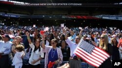 Orang-orang bersorak setelah mengucapkan janji setia dalam upacara naturalisasi bagi 755 warga negara AS yang baru di Turner Field, Atlanta (16/9). (AP/David Goldman)