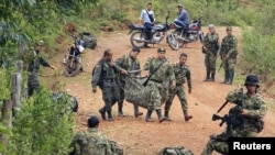 Colombian soldiers carry the weapons of comrades killed after a rebel attack in La Esperanza village, April 15, 2015.