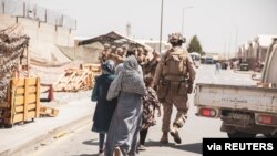 Un infante de Marina de EE. UU. escolta una familia durante la evacuación en el aeropuerto de Kabul, Afganistán, el 21 de agosto de 2021.