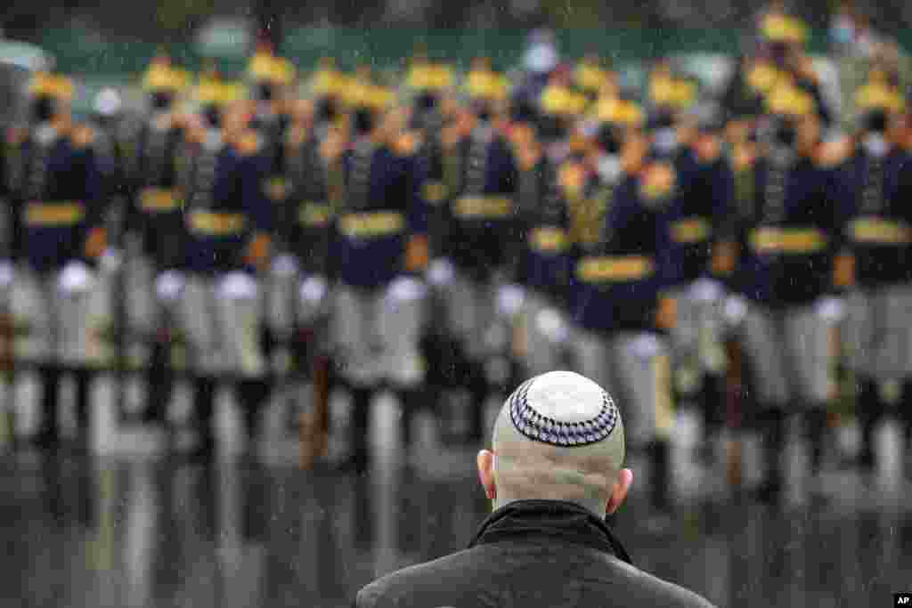 A member of parliament representing the Jewish community speaks, backdropped by mask-wearing members of an honor guard, outside the Holocaust memorial during the National Holocaust Remembrance Day commemorations in Bucharest, Romania.