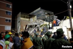 Rescue workers search through rubble during a floodlit search for students at Enrique Rebsamen school in Mexico City, Mexico, Sept. 20, 2017.