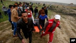 Medics and protesters evacuate a youth who was shot by Israeli troops near the Gaza Strip's border with Israel while marking first anniversary of Gaza border protests east of Gaza City, March 30, 2019.